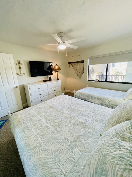 Queen and twin beds with a 50” TV, books and toys.