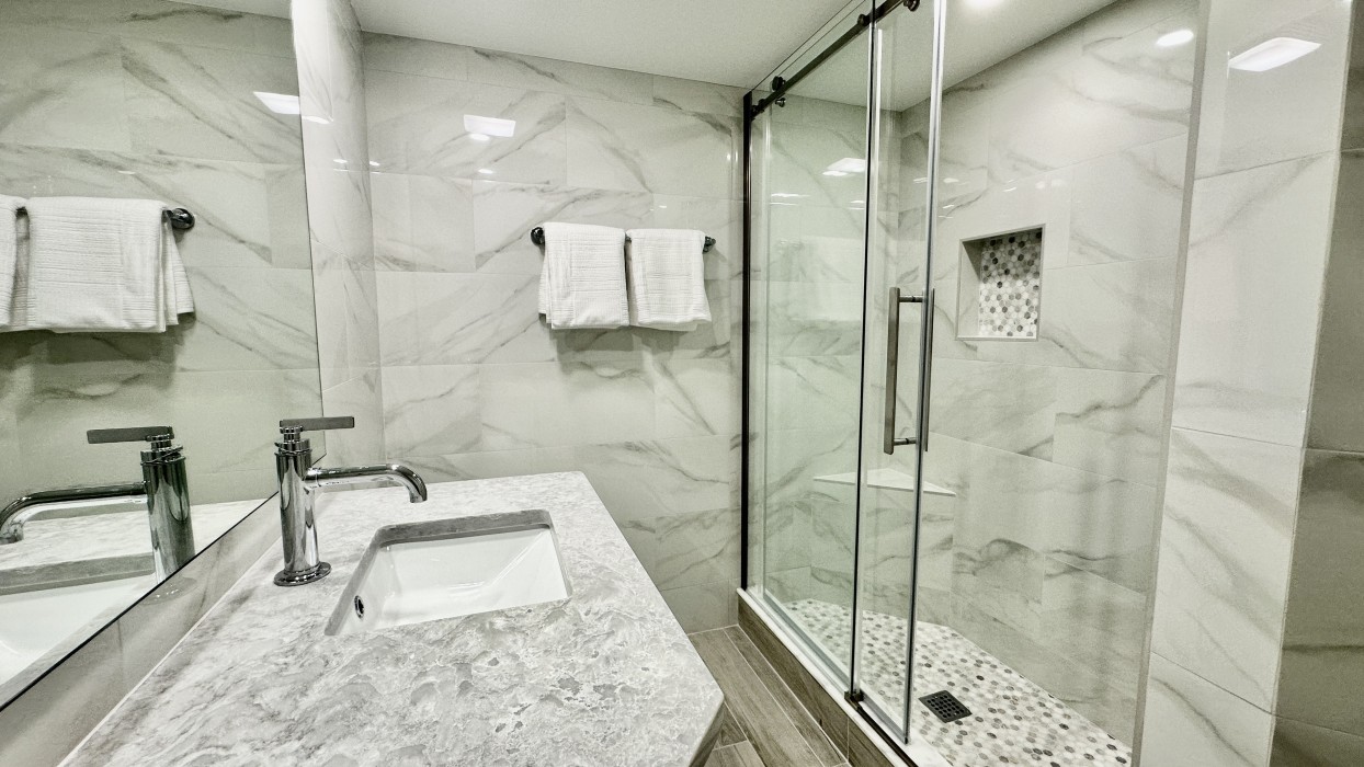 The guest bathroom features an oversized vanity and custom shower.