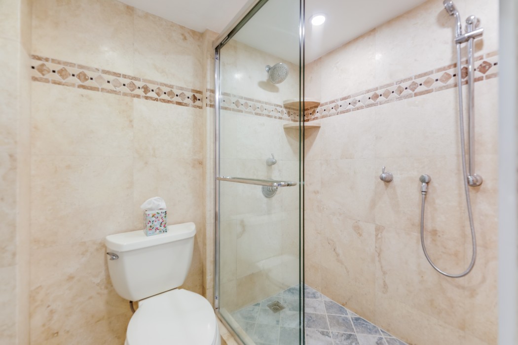 Extra long shower with a bench seat, wall rain shower head and a separate shower wand.