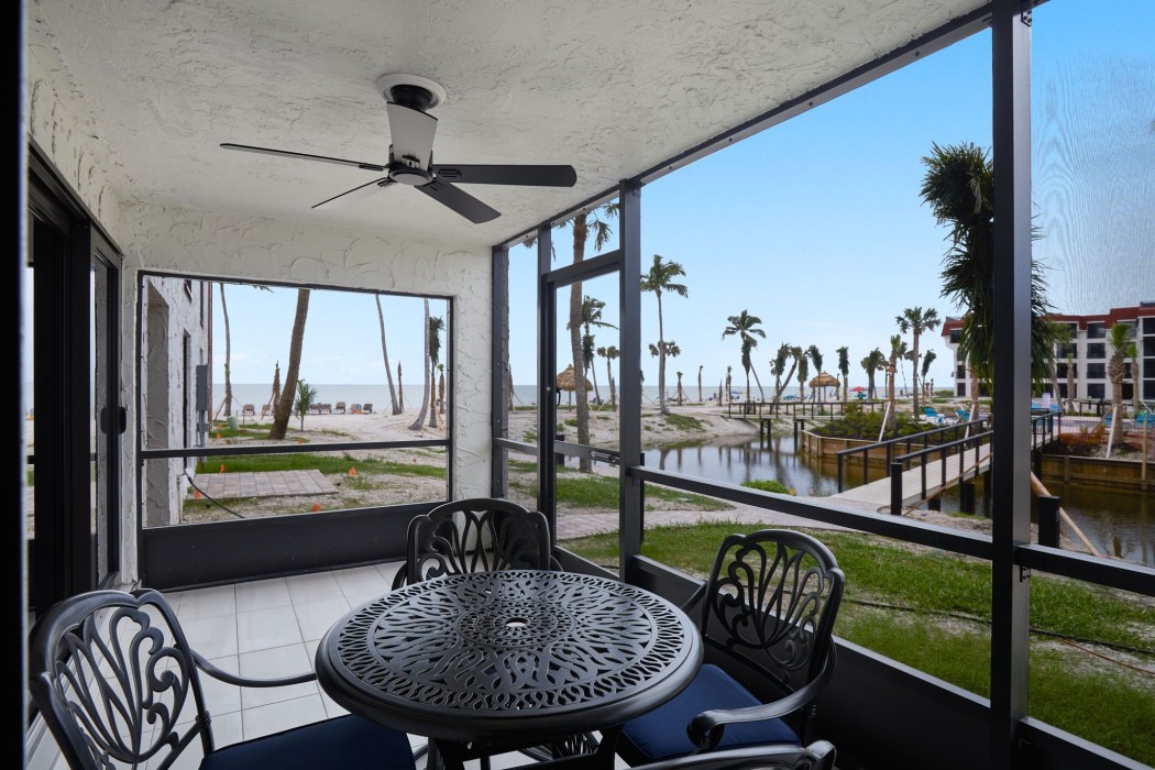 Lanai table and chairs and view of the pool and beach only steps away